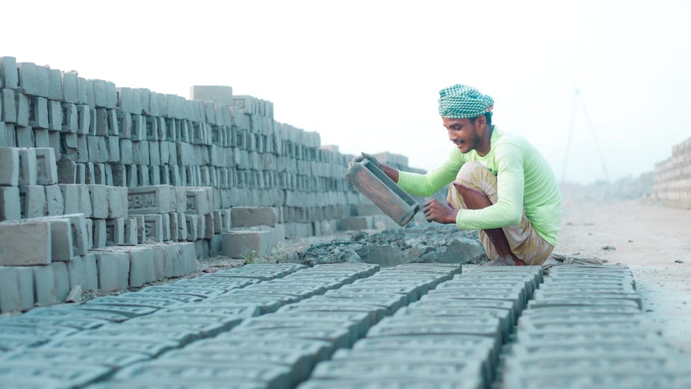 A mason at work shaping bricks by hand on the job.